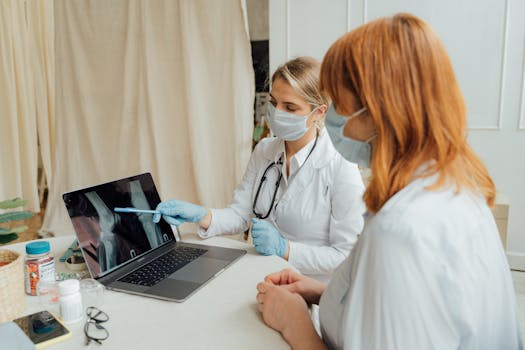 Doctor explains X-ray results to patient using a laptop in a clinic setting.