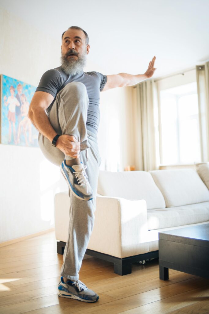 Elderly man practicing yoga at home, demonstrating balance and fitness in the living room.